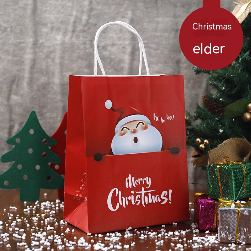 Red Christmas gift bag with Santa illustration and "Merry Christmas" text. Surrounded by a small Christmas tree, presents, and scattered faux snow on a wooden surface.