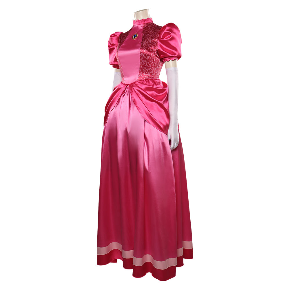 Pink satin gown with puffed sleeves, lace bodice, and gemstone brooch. The floor-length skirt features pleats and white trim. White gloves complete the elegant ensemble.
