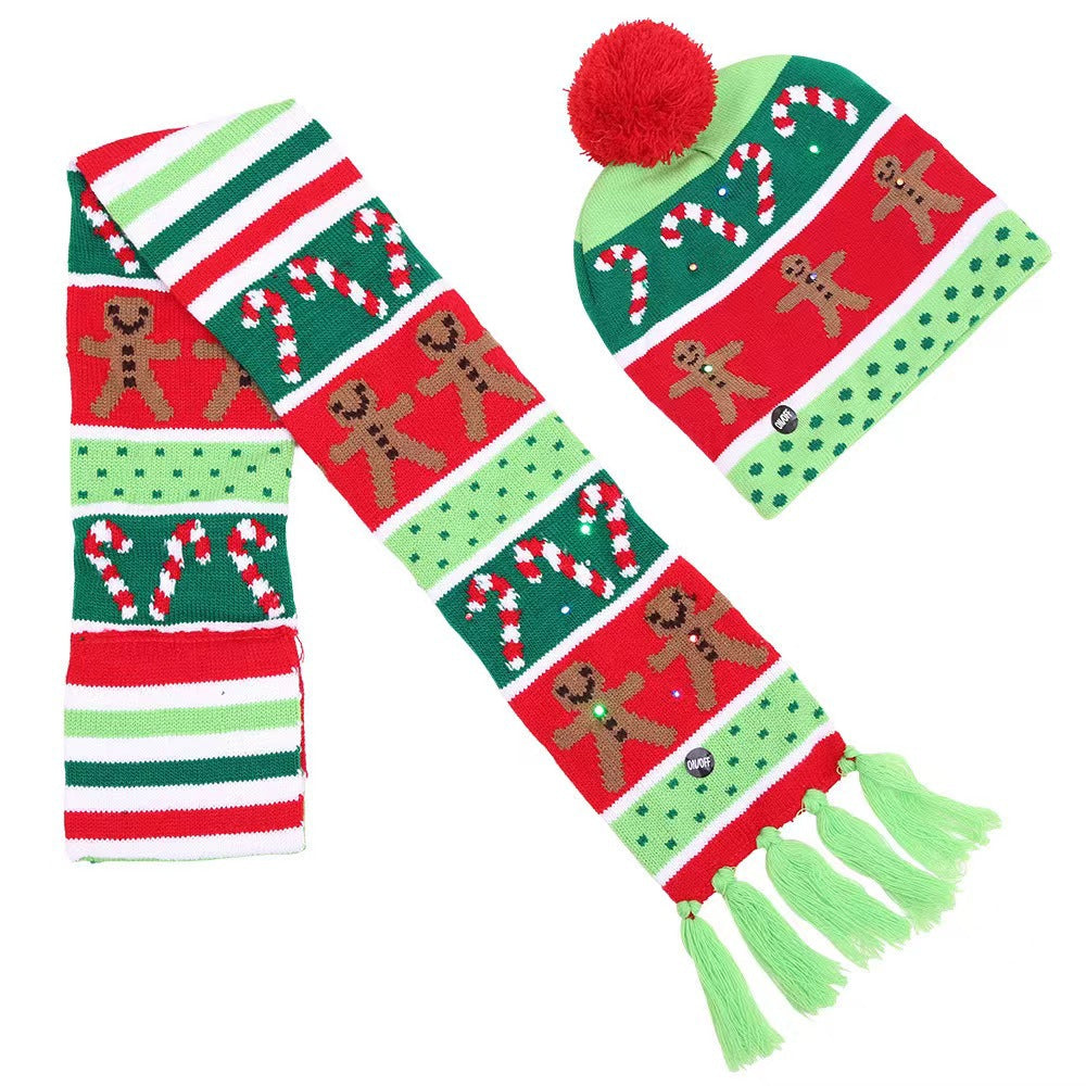 Colorful knit hat and scarf set featuring gingerbread men, candy canes, and stripes in red, green, and white. The scarf has green tassels, and the hat is topped with a red pom-pom.