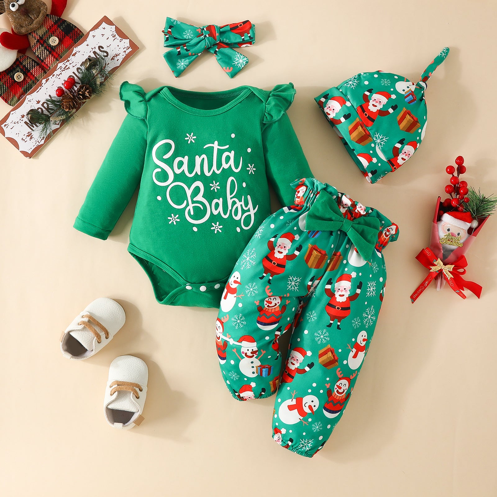 Green "Santa Baby" onesie, Santa-themed pants, hat, and bow on beige background. Includes white baby shoes and Christmas-themed decorations for a festive look.