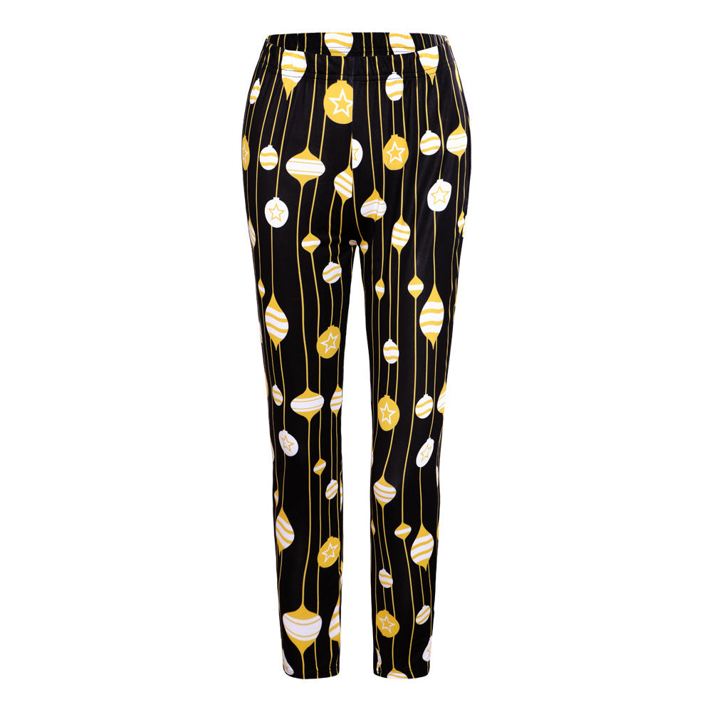 Black pants with a festive pattern of hanging ornaments in yellow and white, featuring stars and striped designs, arranged vertically.