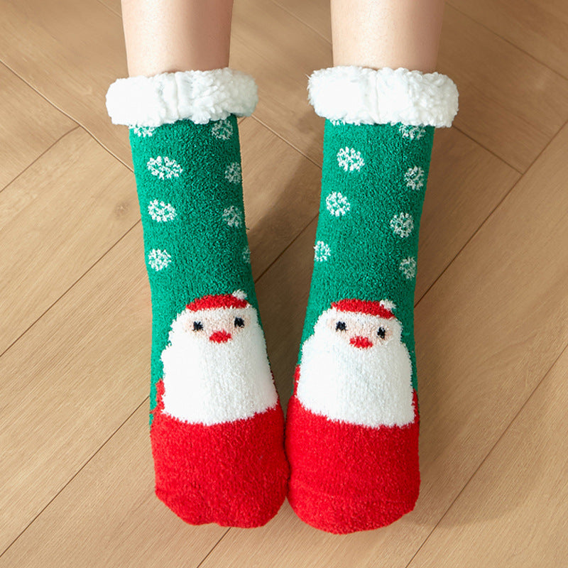 Cozy green socks with white snowflakes and red Santa Claus design, featuring fluffy white cuffs. The socks are worn on feet standing on a light wooden floor.