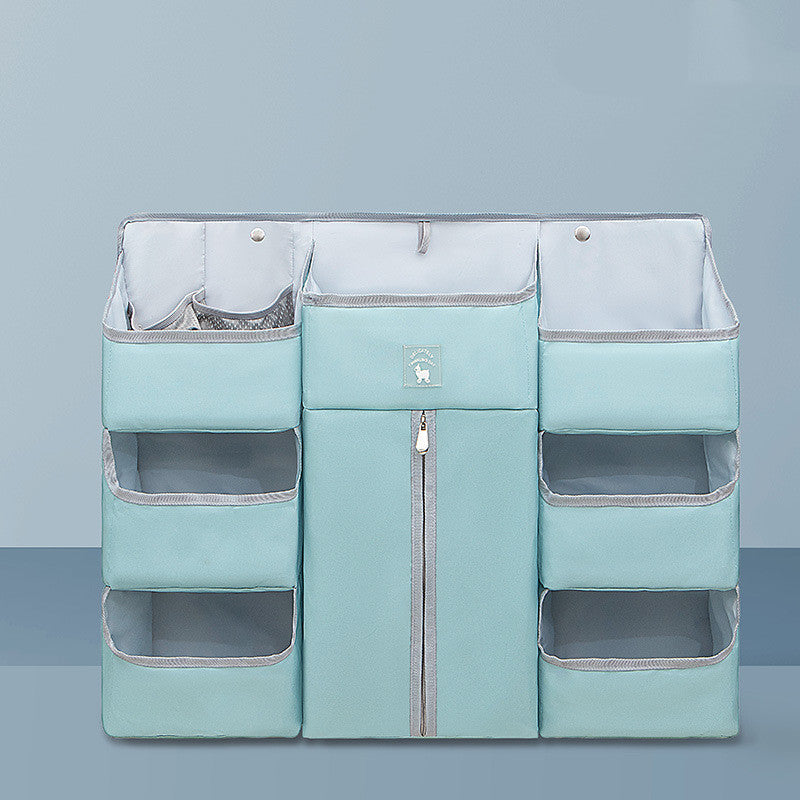 Light blue fabric organizer with multiple pockets and a central zippered compartment, designed for hanging. Made from a soft material with contrasting edges, set against a plain backdrop.