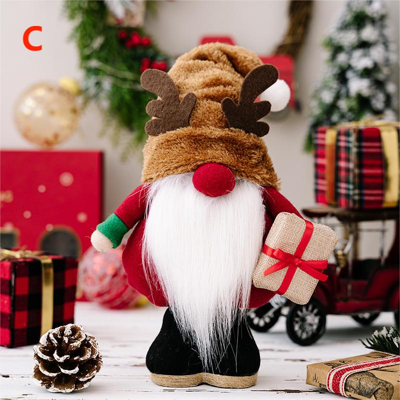 Festive gnome with a long white beard, dressed in red and green, holds a gift with a red ribbon. Decorated with a reindeer hat, Christmas decor surrounds, including wrapped presents and pinecones.