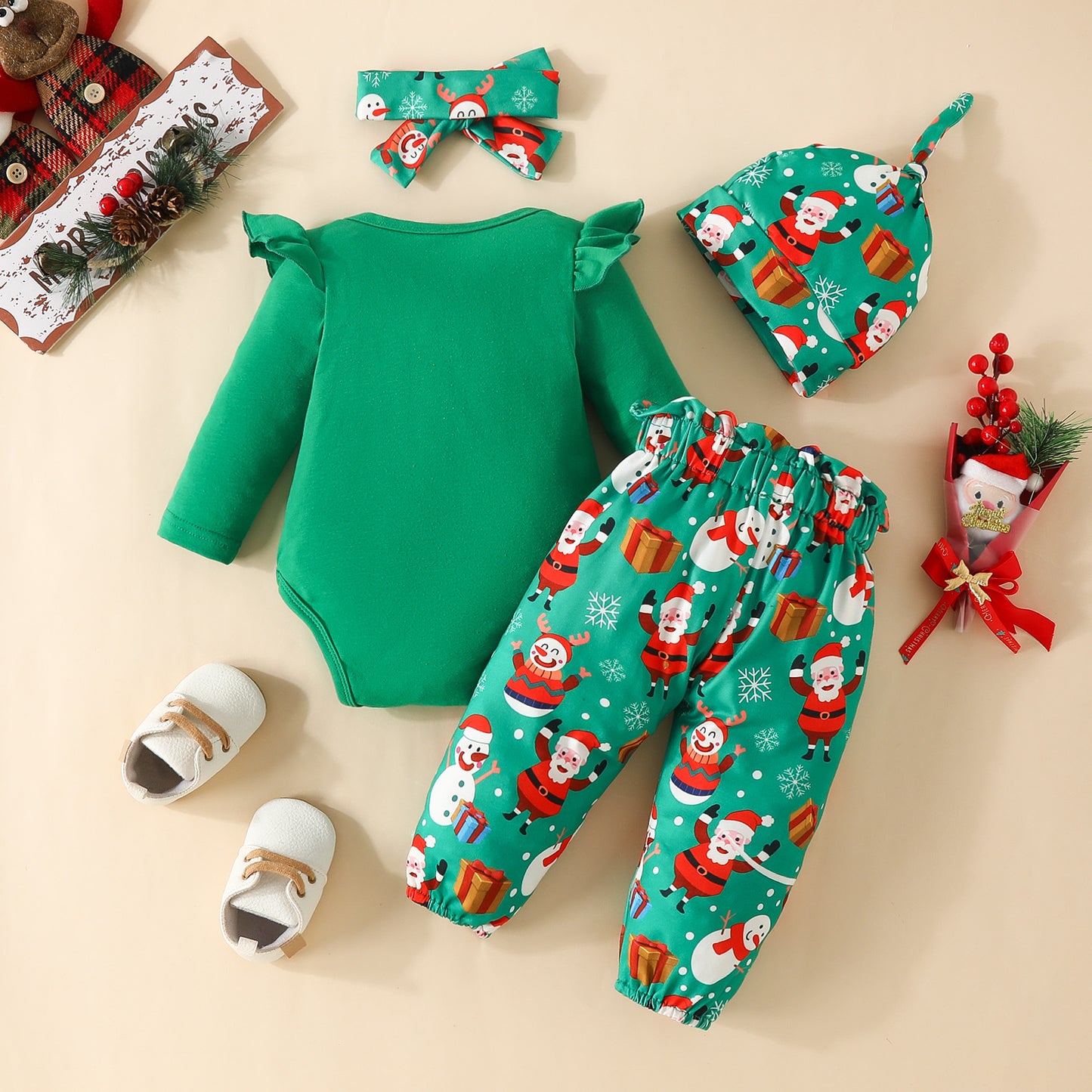 Festive infant outfit with a green onesie, Santa-themed pants, hat, and headband. Includes white shoes and Christmas decorations, featuring Santa and snowmen.