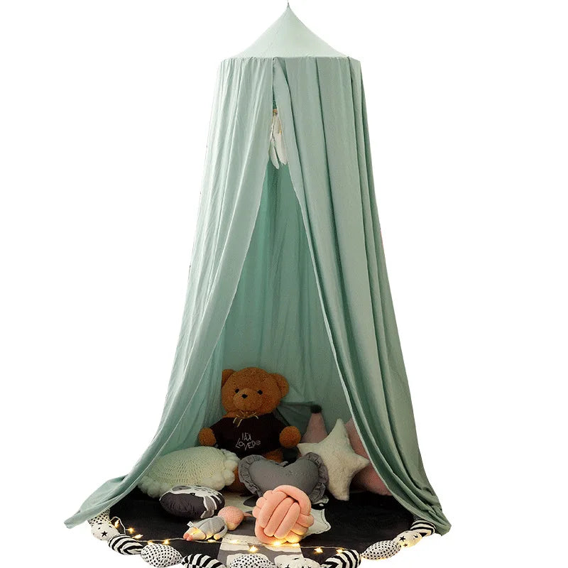Cozy play tent with light green drapes, featuring a teddy bear, cushions, and plush toys inside. A string of lights encircles the entrance, creating a whimsical atmosphere.