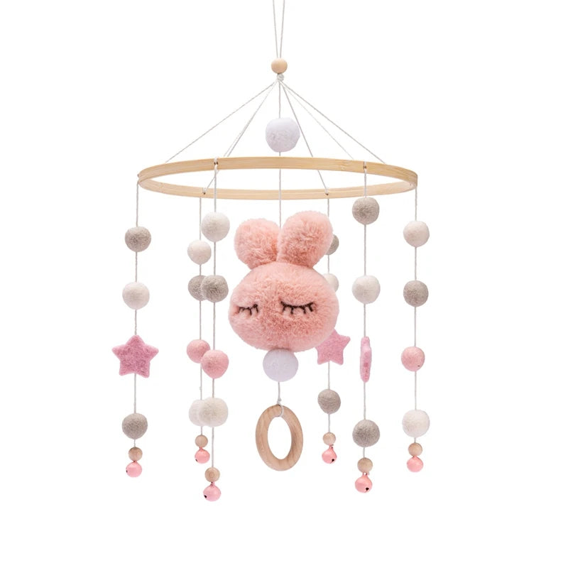 Hanging baby mobile with a pink plush rabbit face, stars, and beads. Features wooden ring and pastel colors, suspended from a wooden hoop with strings.