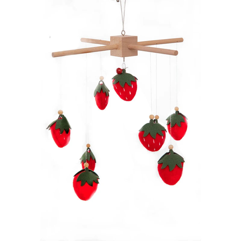A mobile featuring felt strawberries with green leaves hanging from wooden rods. The playful design includes various sizes of bright red strawberries hanging at different lengths.