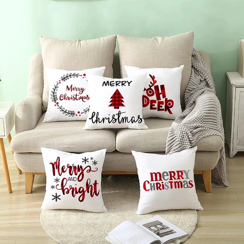 Festive living room with a beige sofa, adorned with six Christmas-themed pillows featuring phrases like "Merry Christmas" and "Merry and Bright." A gray throw is draped over the sofa.
