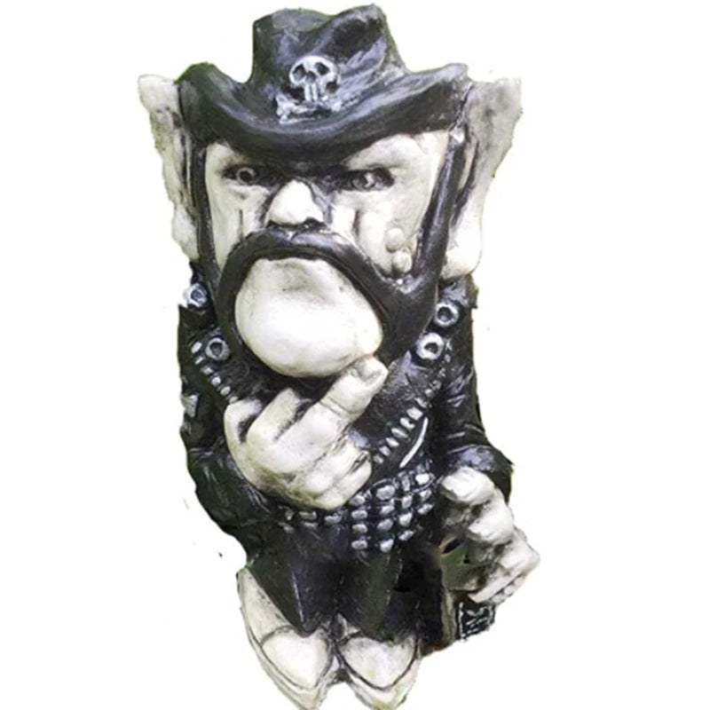 Statue of a gnome-like figure wearing a black hat with a skull emblem, dressed in a black outfit with a prominent mustache, raising its middle finger, exuding a rebellious vibe.