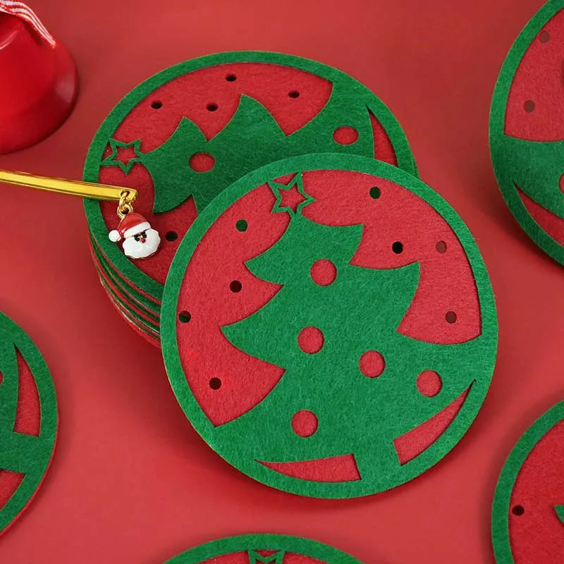Green felt coasters with a cut-out Christmas tree design, layered over red. A pencil with a Santa charm is placed on the stack against a red background.