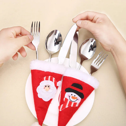 Hands arrange cutlery in festive red holders with Santa and snowman designs, placed on a white plate against a beige background.