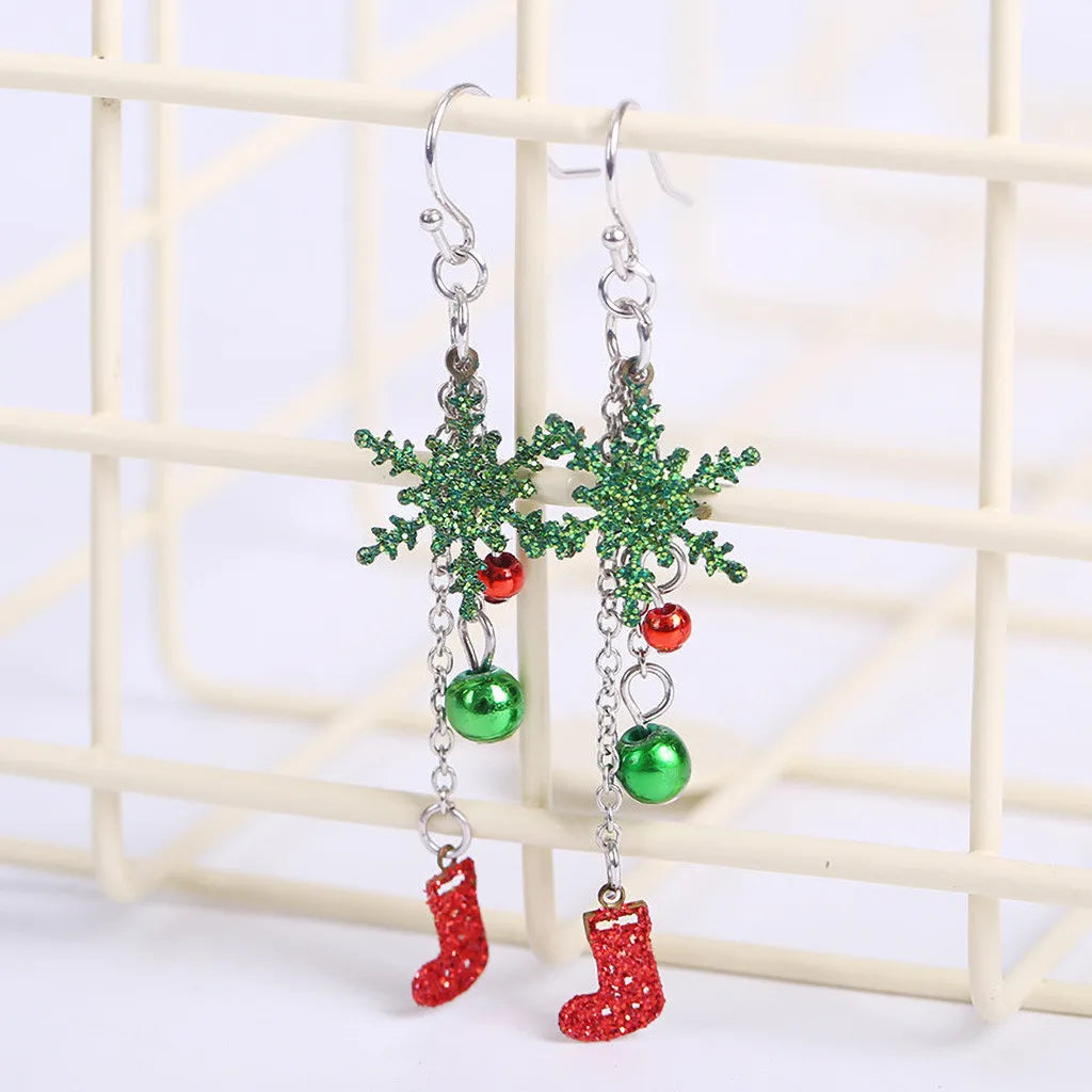 Festive earrings featuring green glitter snowflakes, red and green baubles, and dangling red glitter stockings, hanging on a grid background.