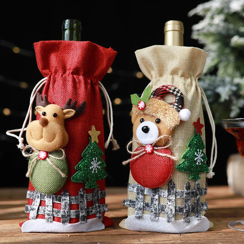 Festive wine bottles wrapped in holiday-themed burlap bags, one red with a reindeer and the other beige with a teddy bear, both decorated with stars and Christmas trees.
