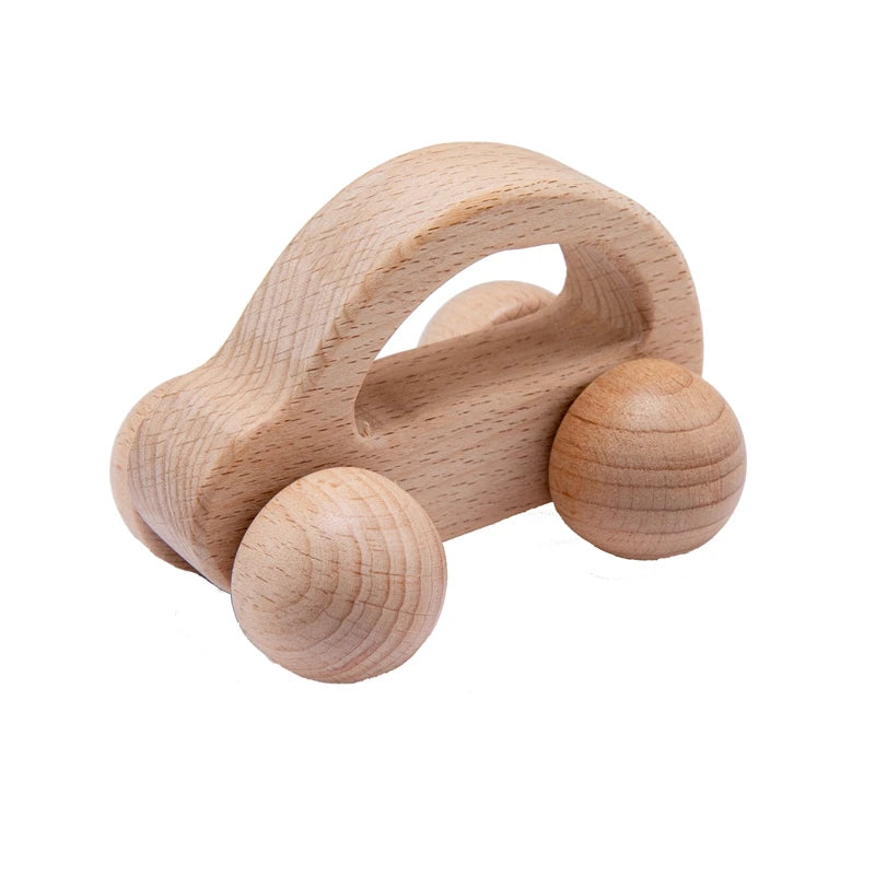 Wooden toy car with rounded edges, featuring a handle-like arch on top and four spherical wheels. The natural wood grain is visible, giving it a simple, handcrafted appearance.