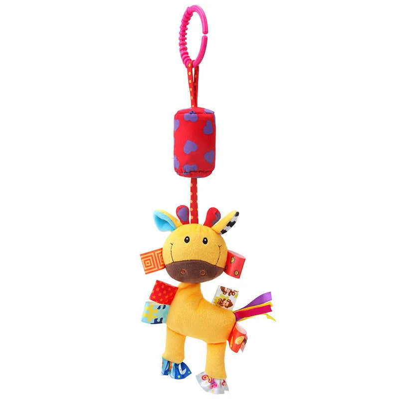 A colorful plush giraffe toy with multi-patterned tags and a red hanging loop. The toy is suspended by a red cylinder with blue hearts, featuring a yellow body and playful details.