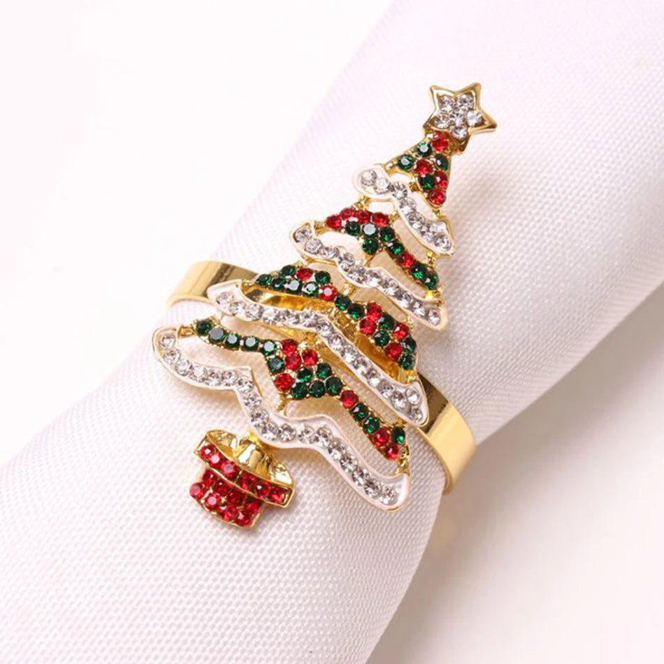 Festive napkin ring designed as a Christmas tree adorned with red, green, and white crystals, set on a gold band, wrapped around a white napkin.
