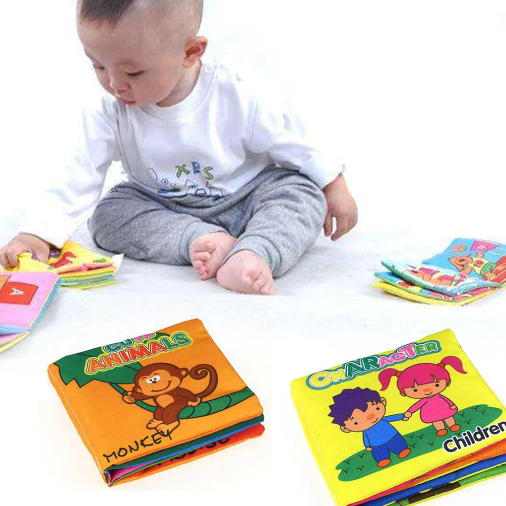 A baby sits on the floor, wearing a white shirt and gray pants, playing with colorful cloth books featuring cartoon animals and characters.