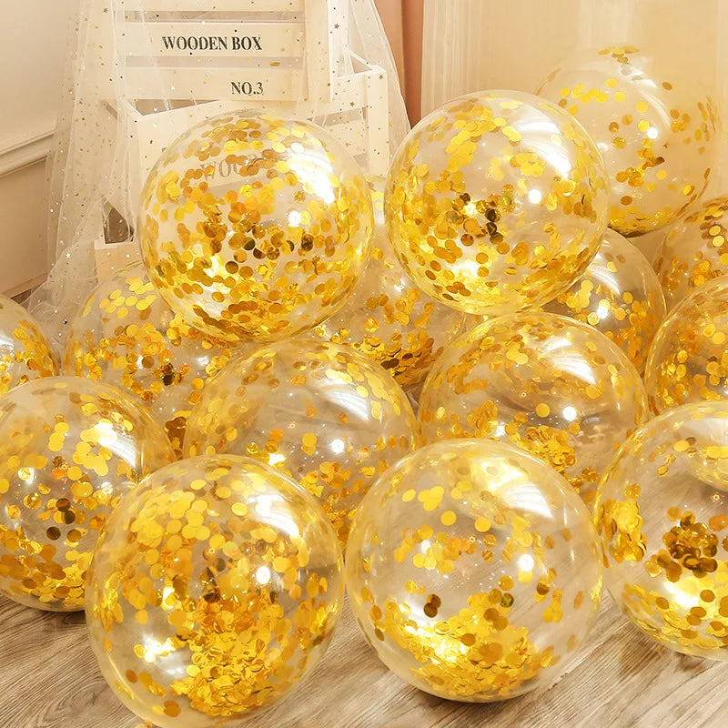 Clear balloons filled with shiny gold confetti are scattered on a wooden floor. A sign behind reads "Wooden Box No.3", draped with sheer fabric.