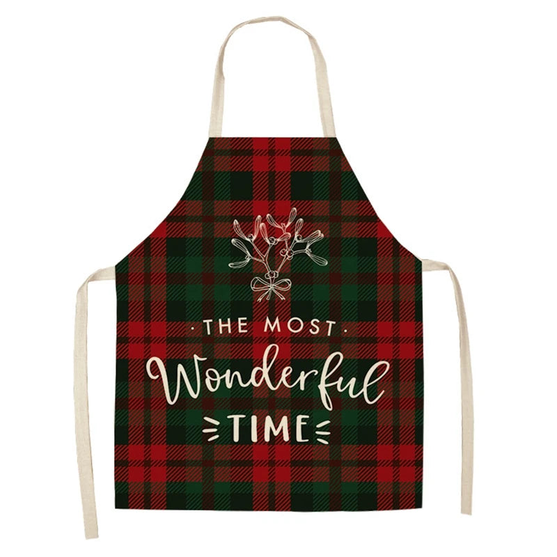 Red and green plaid apron with a mistletoe design and the text "The Most Wonderful Time" in white cursive and block letters. Beige neck and waist straps.