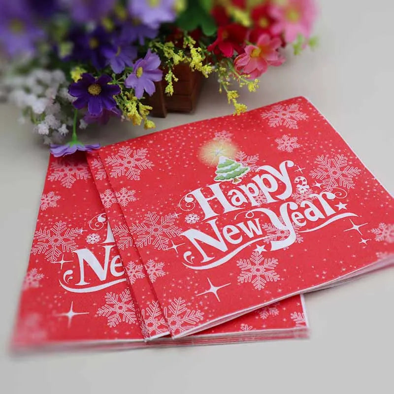 Red cards with "Happy New Year" in white, adorned with snowflakes and a Christmas tree, placed next to colorful flowers.