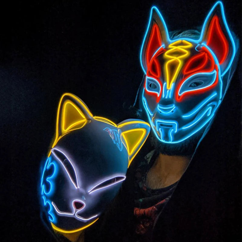 Two people wearing illuminated masks: one with a feline shape featuring yellow and blue outlines, and another with a futuristic design in blue, red, and yellow lines.