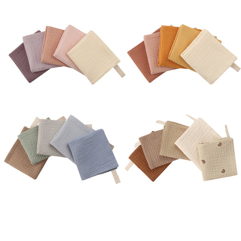 A collection of soft, textured square cloths arranged in four groups. Each group features a different color palette, including pastels, earth tones, and patterned designs.