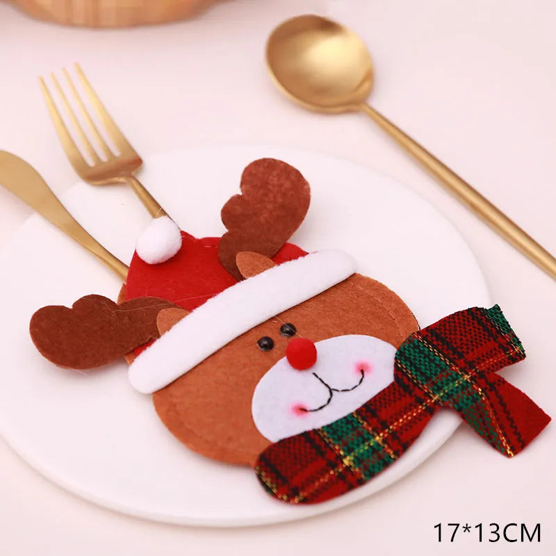 Festive reindeer-themed felt cutlery holder with Santa hat and plaid scarf on a plate, accompanied by a gold fork and spoon. Dimensions noted as 17x13 cm.