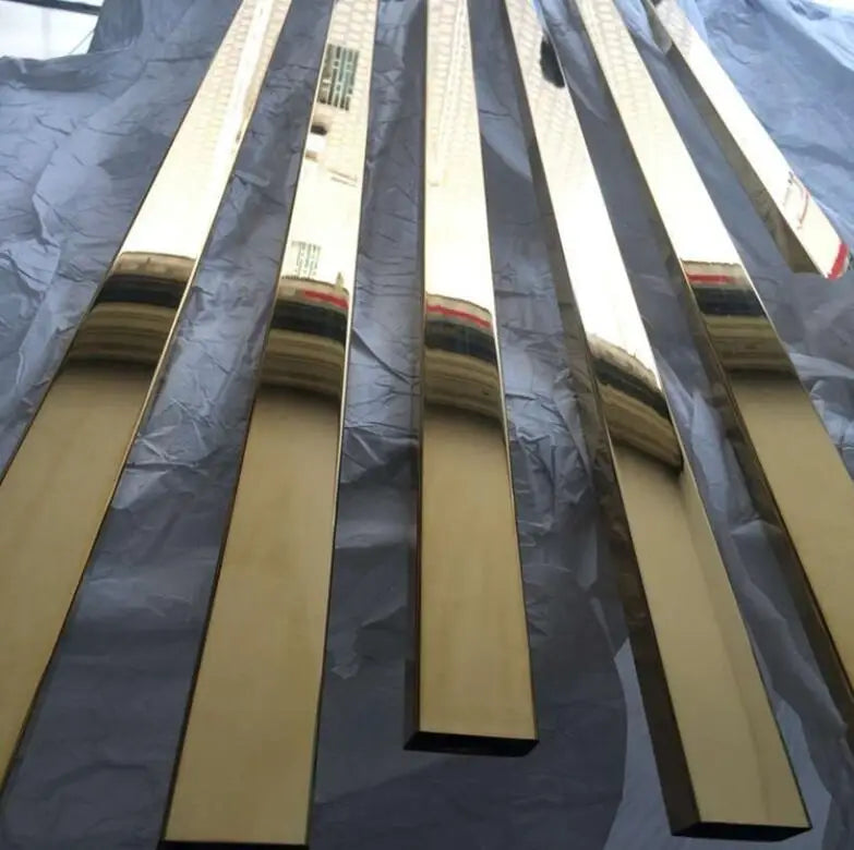 Shiny gold metal bars reflecting a building's facade lie parallel on a crumpled, gray surface, creating a sleek, modern aesthetic.
