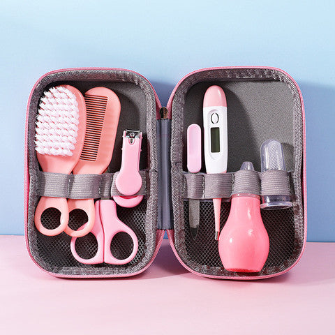 Pink baby care kit with grooming tools: brush, comb, scissors, nail clippers on left; digital thermometer, nasal aspirator, and liquid dropper on right, in a pink and gray case.
