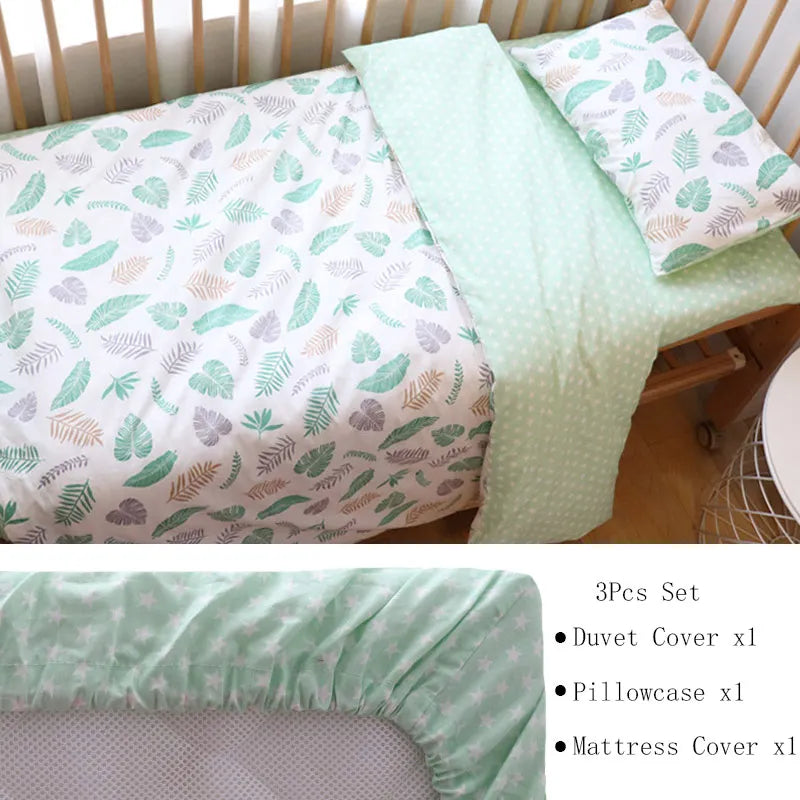 Leaf-patterned bedding set with a mint green duvet cover, matching pillowcase, and mattress cover. The design features soft, colorful leaves in a cozy wooden crib setting.