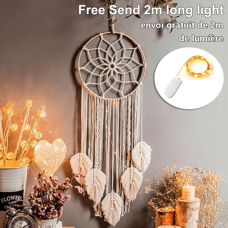 Decorative dream catcher with leaf-shaped tassels on a wall with warm string lights. Nearby are lit candles, flowers, and a clock. Text reads “Free Send 2m long light.”