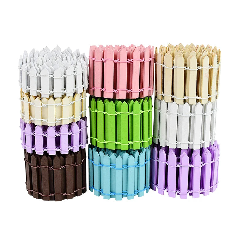 Stacked rolls of colorful mini picket fences in hues of white, pink, beige, brown, green, blue, and purple, wrapped in white string, arranged in two columns.