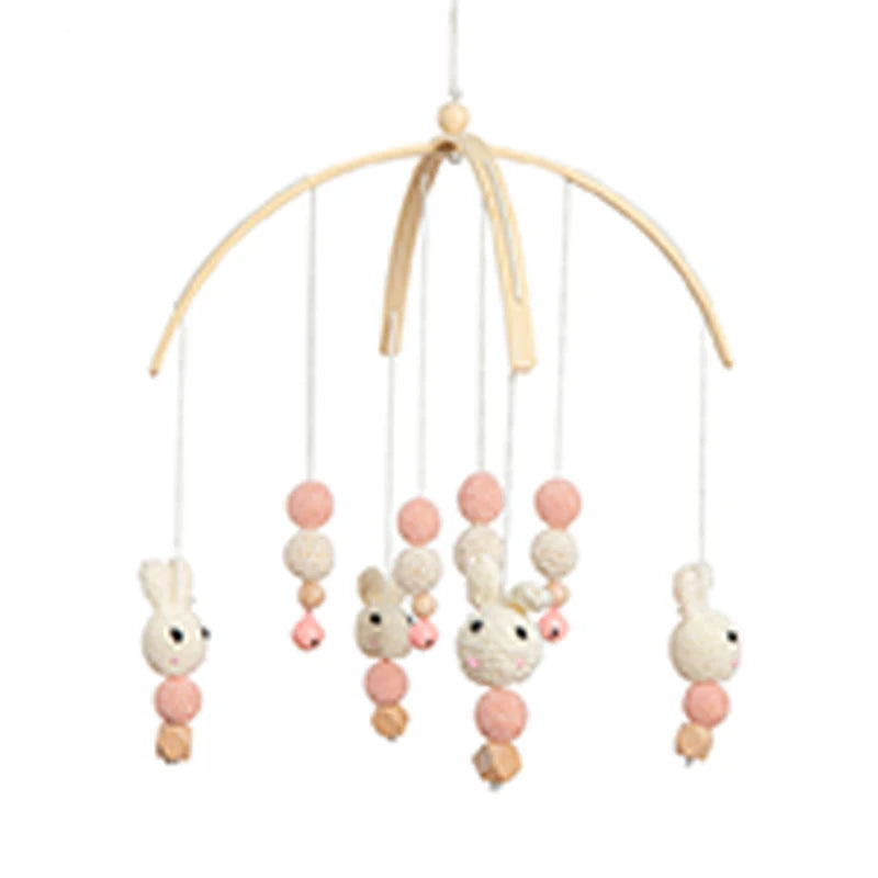 A baby mobile features wooden arches with hanging plush bunnies and pink beads. The gentle pastel colors create a soft, whimsical vibe, perfect for a nursery.