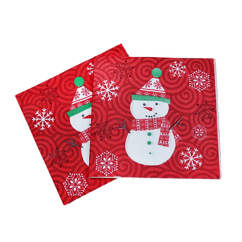 Two festive napkins with snowman designs on a red background featuring swirls and snowflakes. The snowmen have red and green hats, scarves, and buttons.