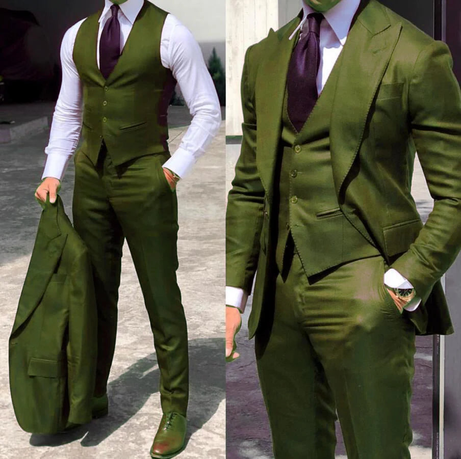 Man in a sharp olive-green three-piece suit with a white shirt and dark purple tie. He holds the suit jacket in one hand and stands confidently.