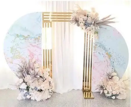 Elegant event backdrop with a golden geometric arch framed by pastel floral arrangements. The circular panel features soft watercolor designs, creating a sophisticated and dreamy setting.