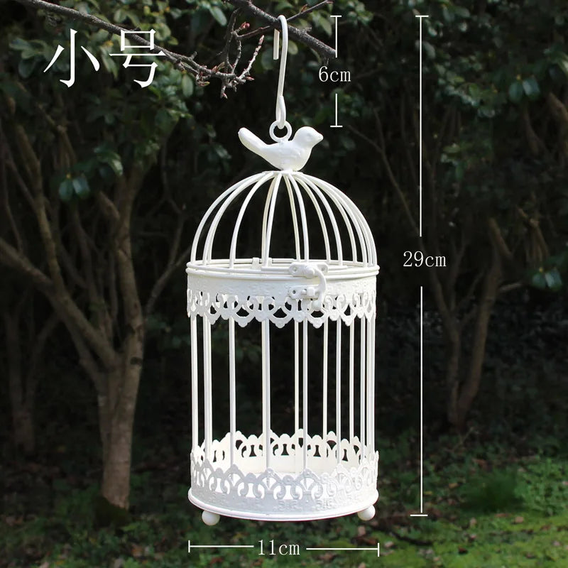 White decorative birdcage with dimensions (29cm height, 11cm diameter) and a bird figure on top, hanging from a tree branch against a leafy background.