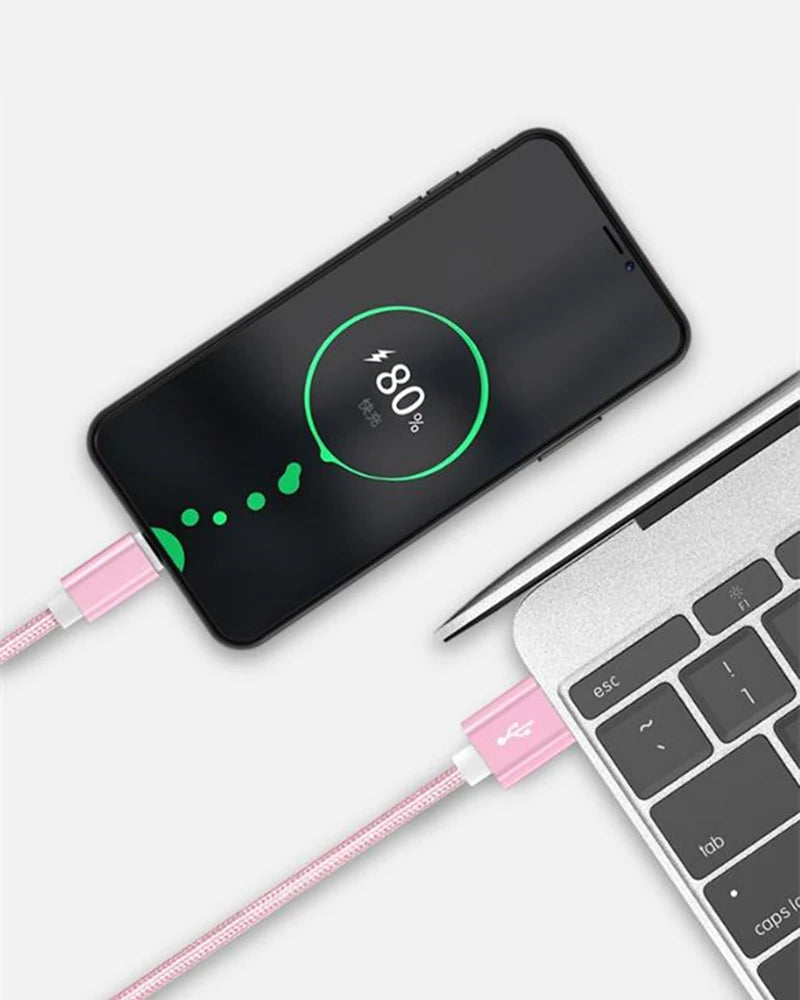Smartphone charging to 80% with pink USB cable connected to a laptop. The phone screen shows a green charging icon and progress on a light gray background.