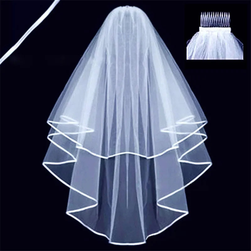 A two-tiered white bridal veil with a comb attachment. The edges are trimmed with white piping. The inset shows a close-up of the veil's comb attachment.