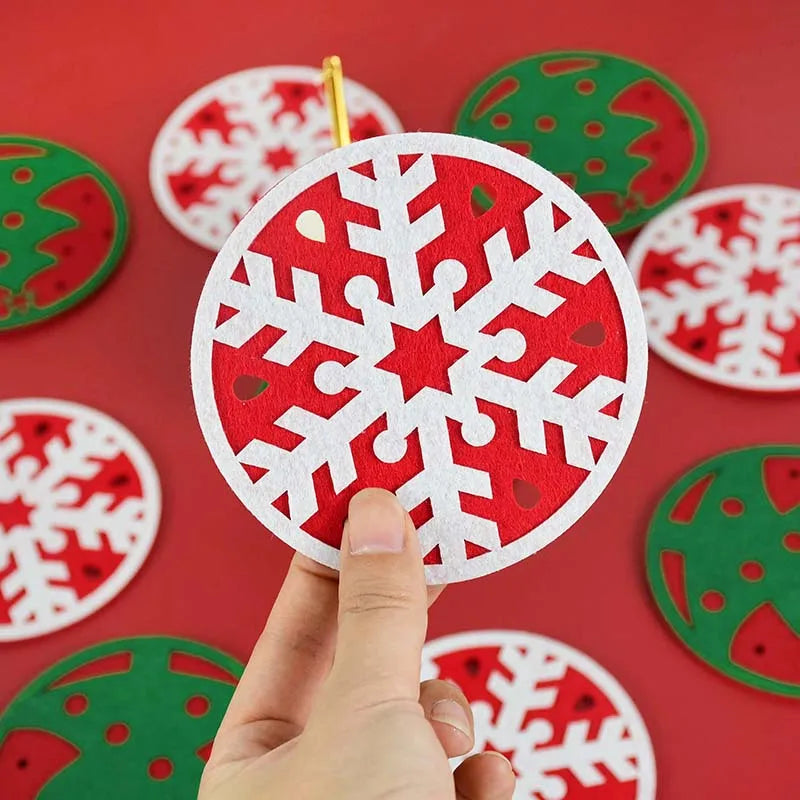 Hand holding a circular red and white snowflake ornament. Background shows various green and red festive ornaments on a matching red surface.
