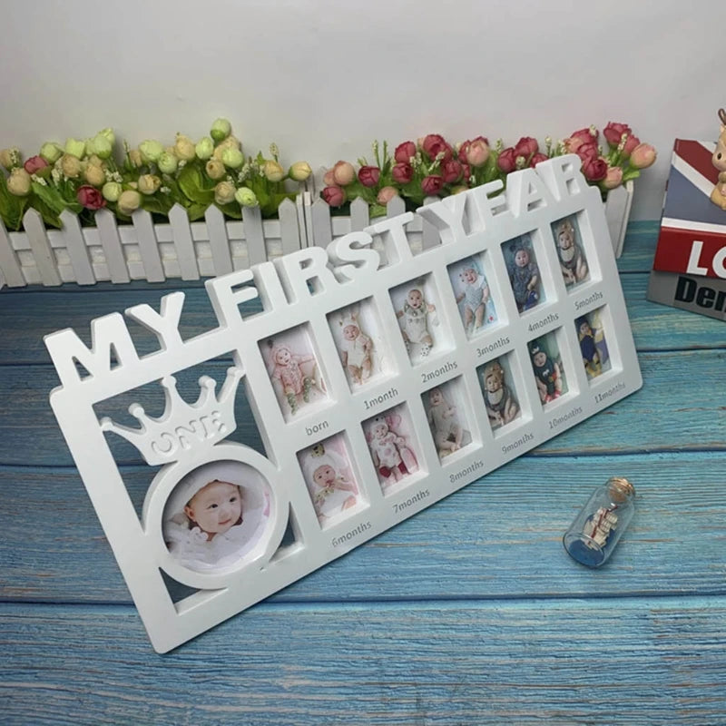 White photo frame labeled "My First Year," with slots for each month from birth to 11 months, and a larger round photo space with a crown design labeled "ONE" on a blue surface.