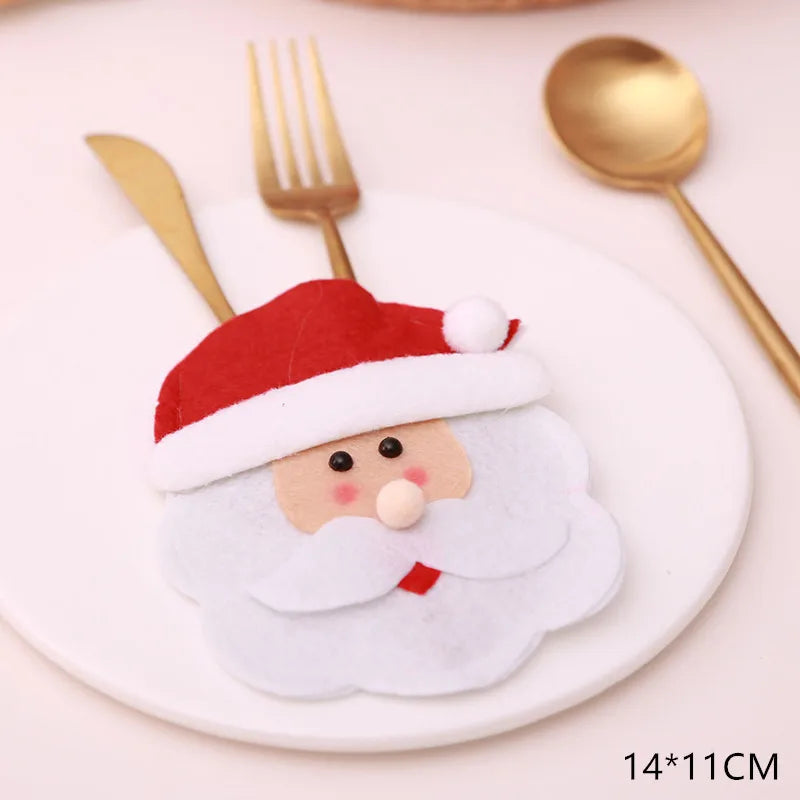 A red and white felt Santa face napkin holder on a white plate, with a gold fork and spoon beside it. The dimensions shown are 14 by 11 cm.