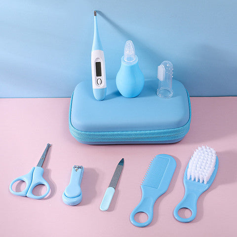 A baby grooming kit with light blue tools, including a thermometer, nasal aspirator, toothbrush, scissors, nail clippers, file, comb, and brush, arranged on a pouch.