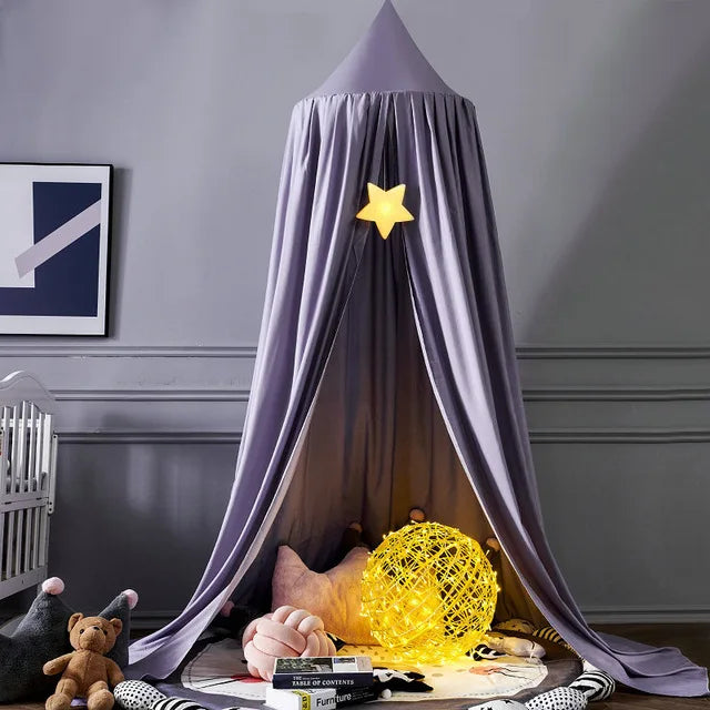 Purple canopy tent with a glowing star and ball light inside, surrounded by plush toys and books on a circular rug. A crib and wall art are in the background.