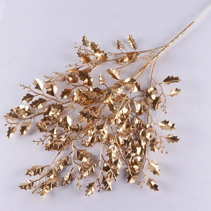 Gold-colored decorative branch with intricately detailed leaves arranged on a light background, showcasing a mix of smooth and jagged edges for an elegant, artistic look.