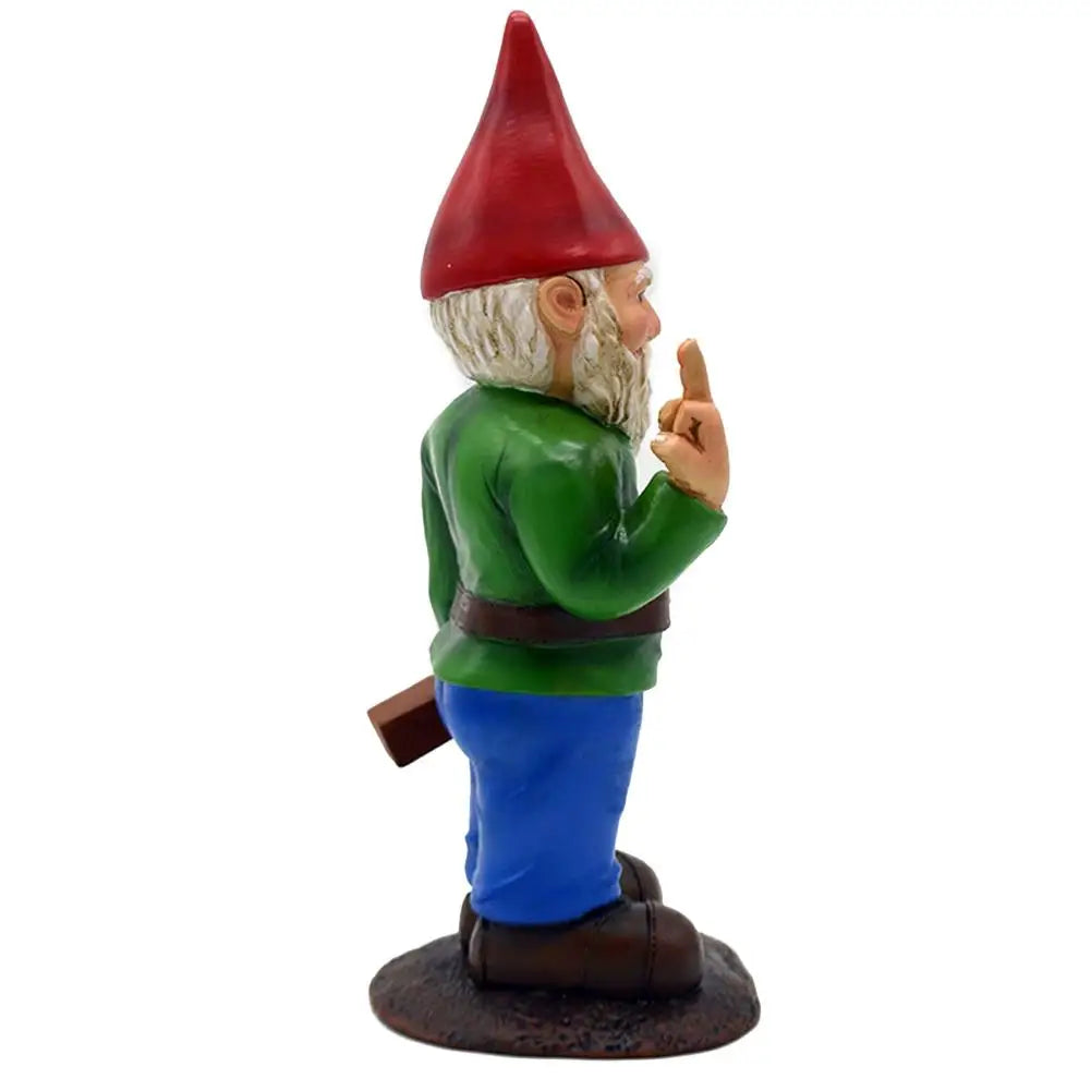 A garden gnome with a red hat, green shirt, and blue pants stands on a base, holding a small object behind its back and gesturing with its finger.