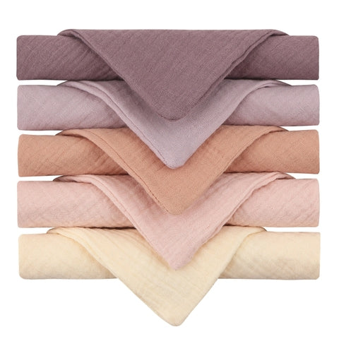 Stack of six folded towels in shades of purple, pink, peach, and cream, arranged in a gradient from top to bottom, highlighting their soft texture and pastel colors.