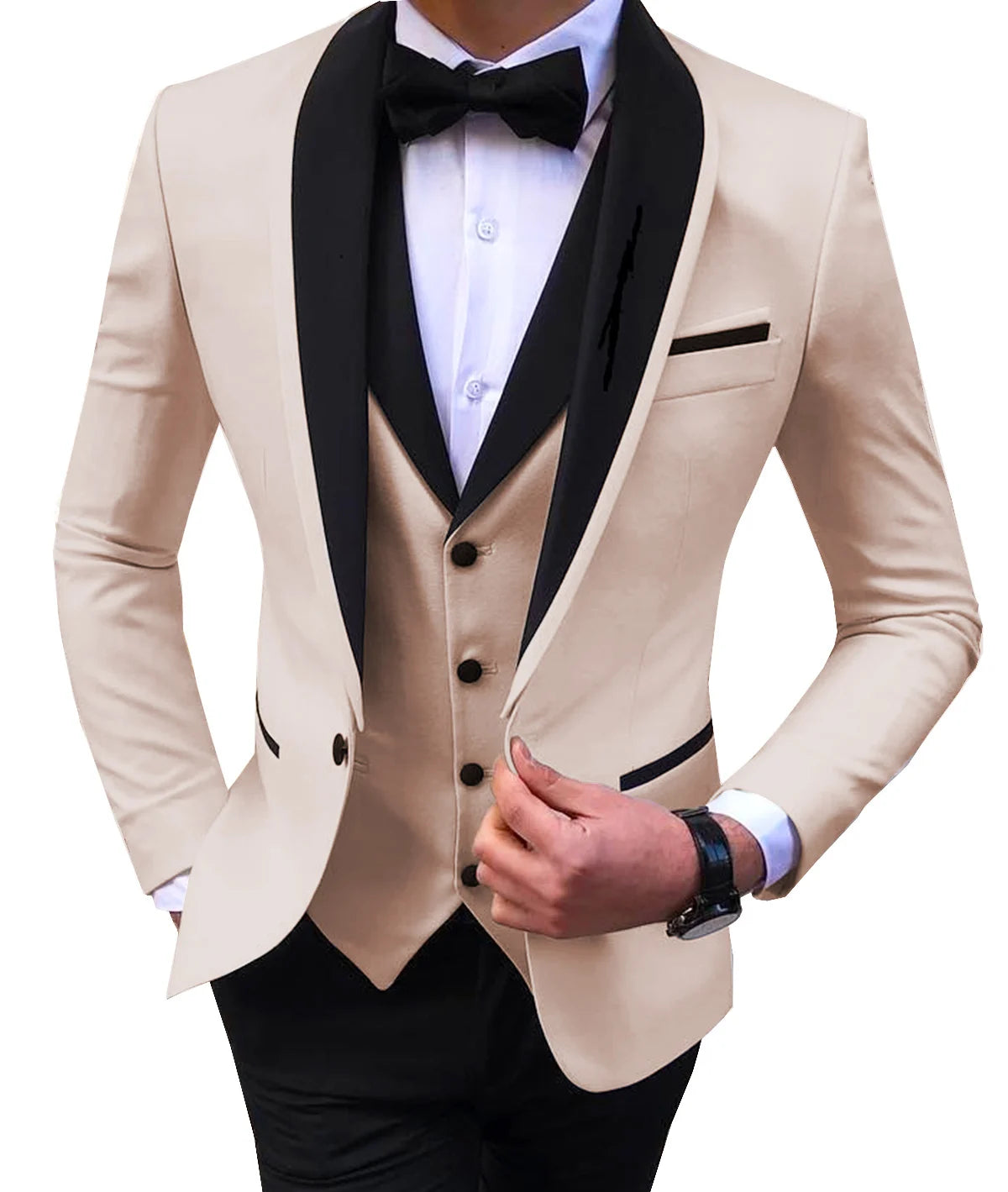 Man wearing a beige tuxedo with black lapels and a black bow tie over a white shirt. He adjusts the jacket with one hand, showcasing a buttoned vest and black pants.