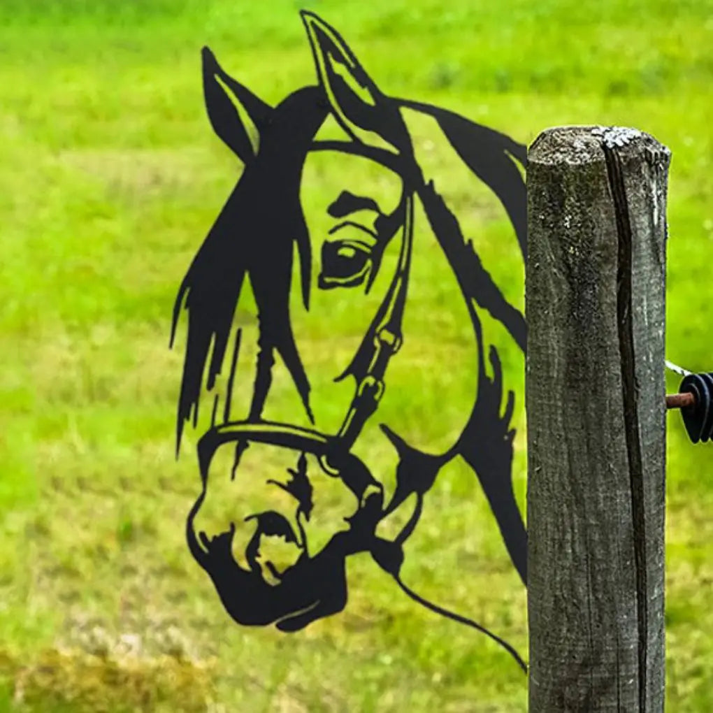 Silhouette of a horse's head on a wooden fence post against a blurred green grass background, creating a striking contrast with its surroundings.